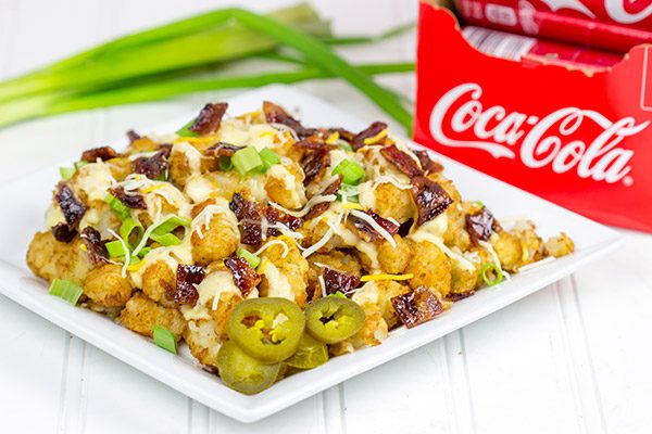 These Loaded Tots are topped with a tasty queso cheese sauce and Coca-Cola glazed bacon bits! They're the perfect snack for watching sports!