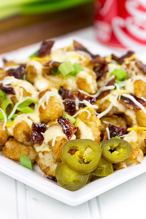 These Loaded Tots are topped with a tasty queso cheese sauce and Coca-Cola glazed bacon bits! They're the perfect snack for watching sports!