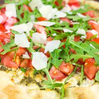 Brushed with pesto and then topped with fresh tomatoes and arugula, this Bruschetta Pizza is a delicious summer meal!