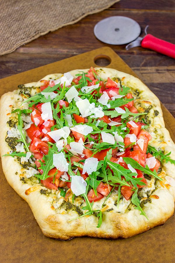 Brushed with pesto and then topped with fresh tomatoes and arugula, this Bruschetta Pizza is a delicious summer meal!