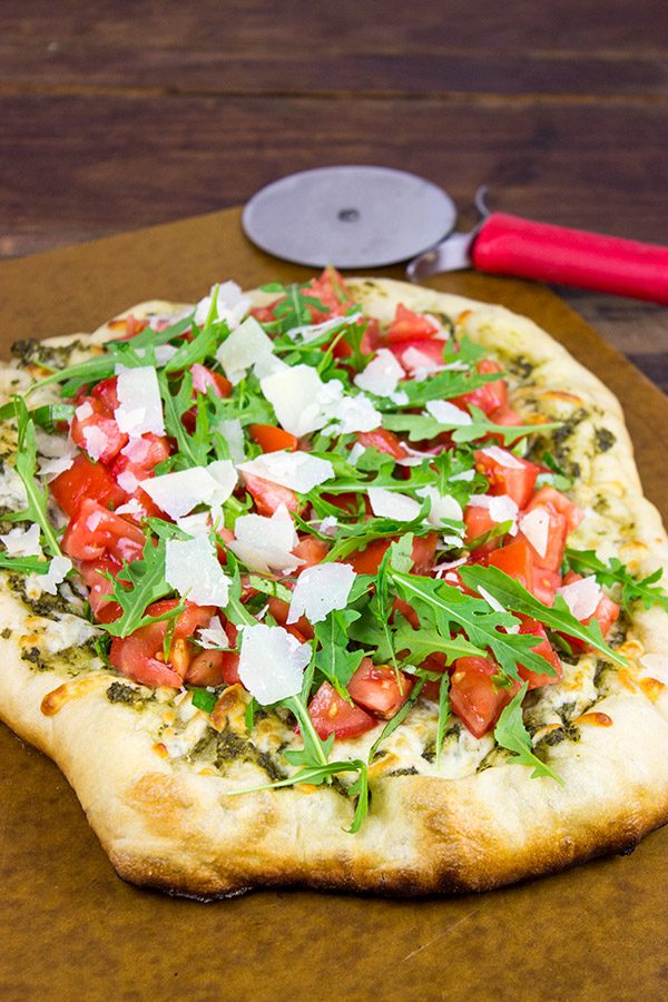 Brushed with pesto and then topped with fresh tomatoes and arugula, this Bruschetta Pizza is a delicious summer meal!