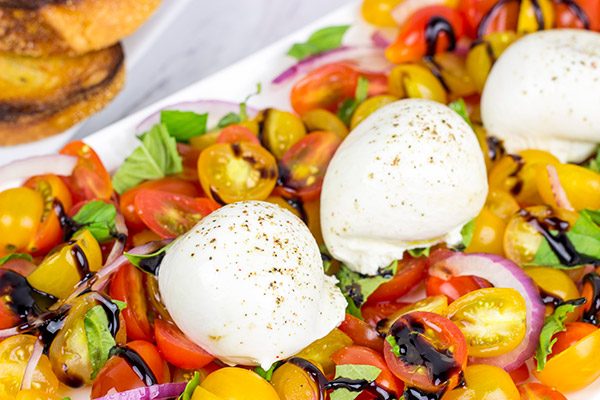 Ever tried burrata cheese? It's in the mozzarella family, and it makes for a great centerpiece of this Tomato and Burrata Caprese!