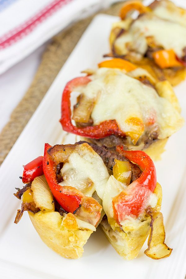 These Philly Cheesesteak Cups feature ribeye steak, peppers and onions all baked in mini crescent roll cups.  They're the perfect comfort food appetizer for football season!