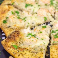 This Shrimp Scampi Pizza is the perfect football food!  Perfectly cooked shrimp combined with a flavorful garlic white sauce make this pizza a tasty option for the big game!