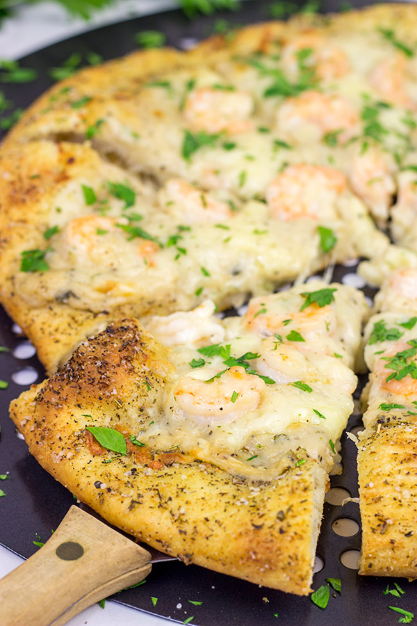 This Shrimp Scampi Pizza is the perfect football food!  Perfectly cooked shrimp combined with a flavorful garlic white sauce make this pizza a tasty option for the big game!