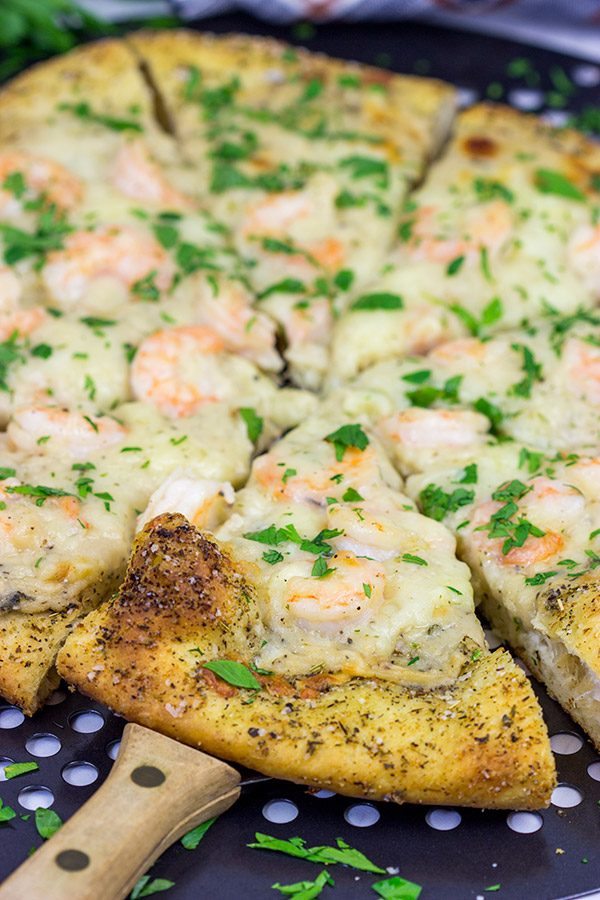 This Shrimp Scampi Pizza is the perfect football food!  Perfectly cooked shrimp combined with a flavorful garlic white sauce make this pizza a tasty option for the big game!