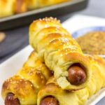 These Cheddar Pretzel Hot Dogs are wrapped with soft pretzel dough and covered with shredded cheese.  Talk about a tasty way to bake up a hot dog!