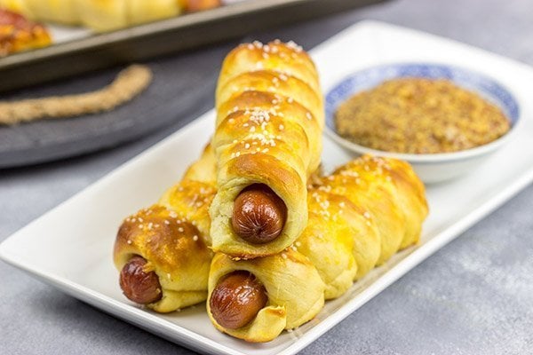 These Cheddar Pretzel Hot Dogs are wrapped with soft pretzel dough and covered with shredded cheese. Talk about a tasty way to bake up a hot dog!