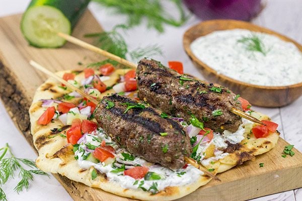Served over grilled naan and tzatziki sauce, these Grilled Beef Kofta Kabobs are a delicious way to enjoy a summer night in the backyard!