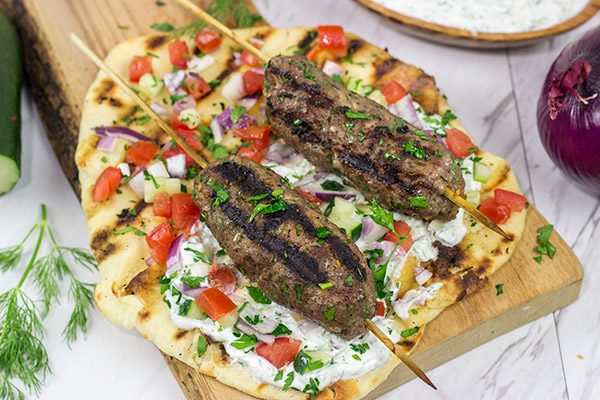 Served over grilled naan and tzatziki sauce, these Grilled Beef Kofta Kabobs are a delicious way to enjoy a summer night in the backyard!