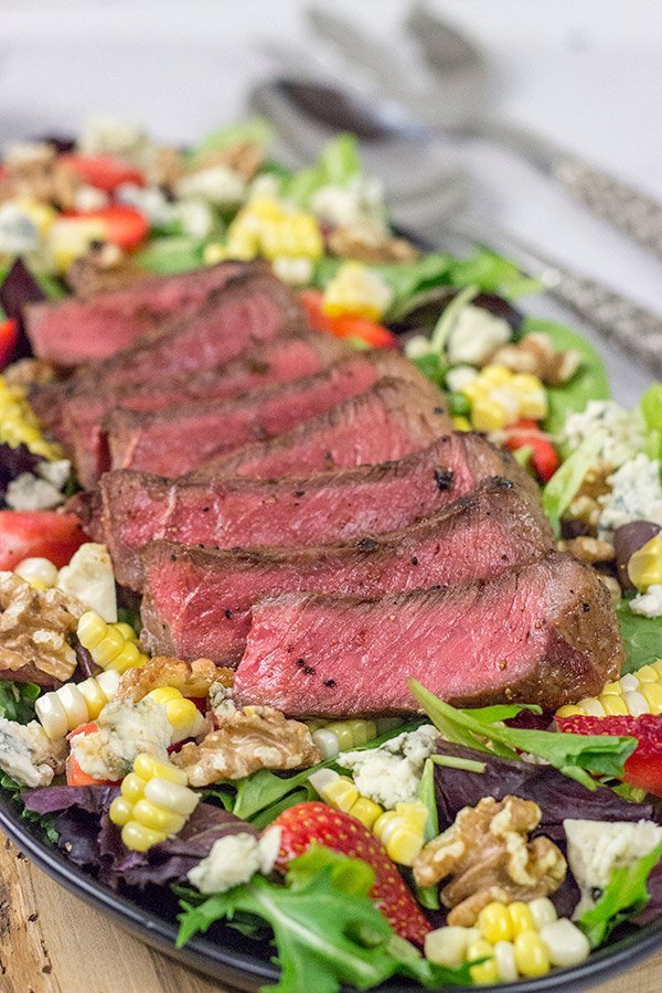 Grilling season is back!  Let's kick it off with a delicious Grilled Steak Salad topped with strawberries, blue cheese, corn and toasted walnuts!