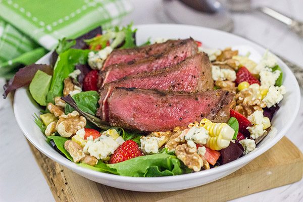 Grilling season is back!  Let's kick it off with a delicious Grilled Steak Salad topped with strawberries, blue cheese, corn and toasted walnuts!