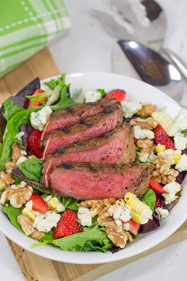 Grilling season is back!  Let's kick it off with a delicious Grilled Steak Salad topped with strawberries, blue cheese, corn and toasted walnuts!