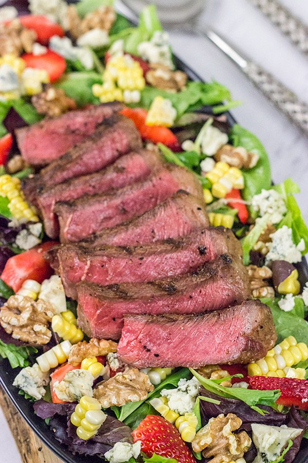 Grilling season is back!  Let's kick it off with a delicious Grilled Steak Salad topped with strawberries, blue cheese, corn and toasted walnuts!