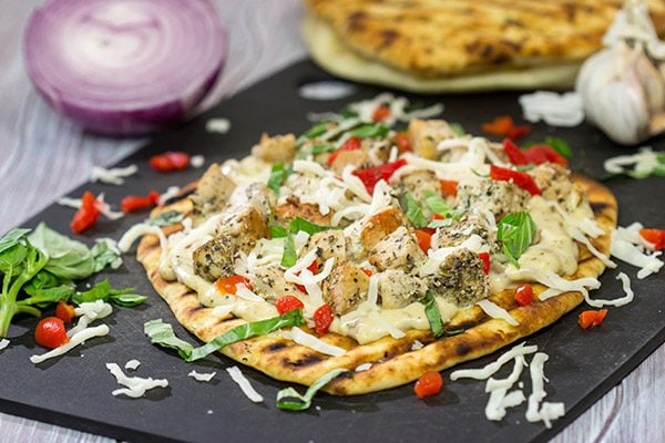 This Grilled Chicken Flatbread features juicy chunks of chicken over a roasted garlic sauce.  Served on tasty naan or flatbread, this recipe will have you coming back for more!
