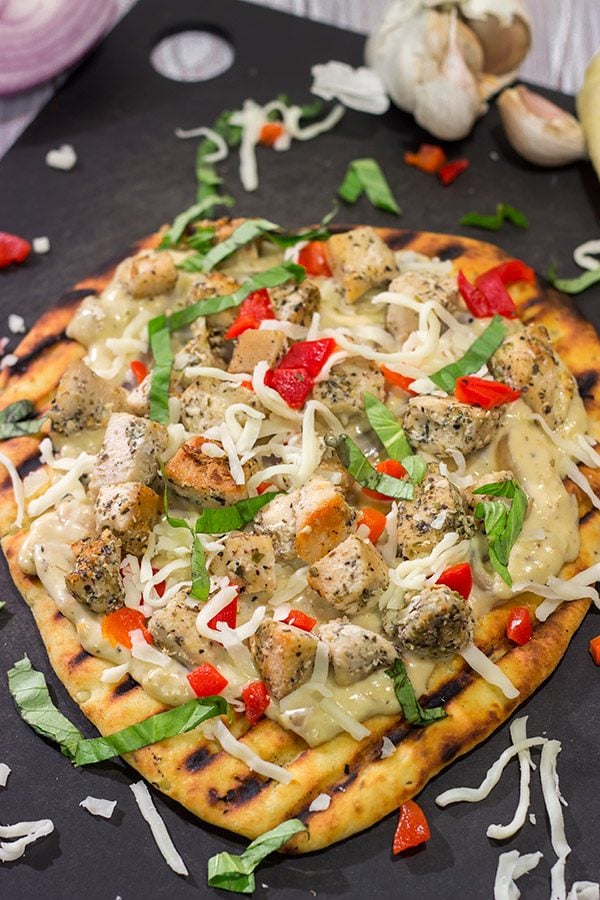 This Grilled Chicken Flatbread features juicy chunks of chicken over a roasted garlic sauce.  Served on tasty naan or flatbread, this recipe will have you coming back for more!