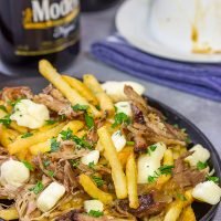 North meets South in this tasty Pulled Pork Poutine recipe. French fries topped with cheese curds, brown gravy and slow-smoked pulled pork make for a delicious appetizer or meal!