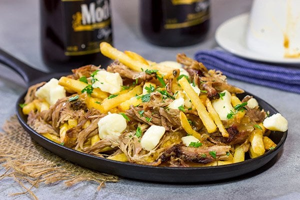 North meets South in this tasty Pulled Pork Poutine recipe. French fries topped with cheese curds, brown gravy and slow-smoked pulled pork make for a delicious appetizer or meal!