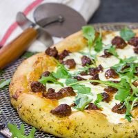 Mix up pizza night! This Italian Sausage and Alfredo Pizza features a delicious alfredo sauce base topped with juicy Italian sausage and fresh arugula!