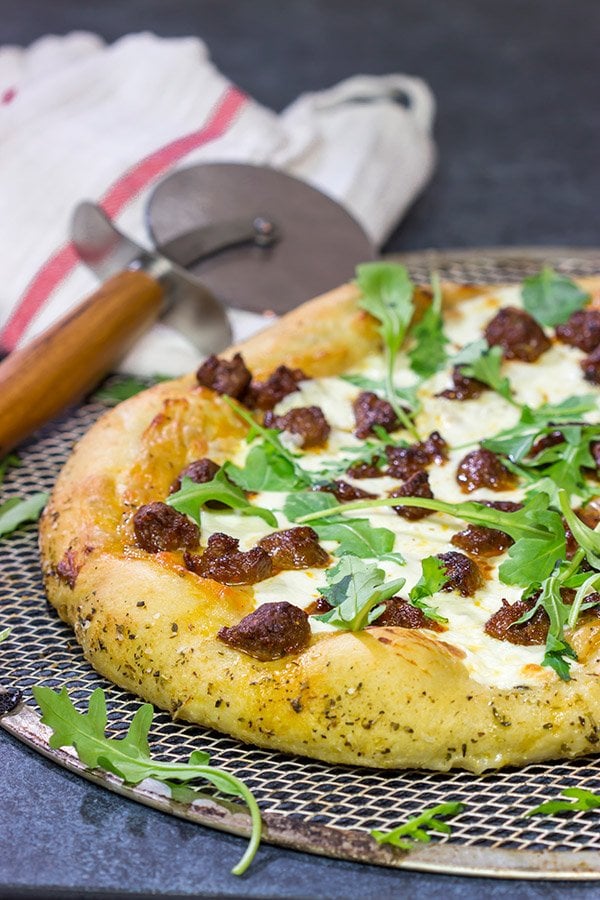 Mix up pizza night! This Italian Sausage and Alfredo Pizza features a delicious alfredo sauce base topped with juicy Italian sausage and fresh arugula!
