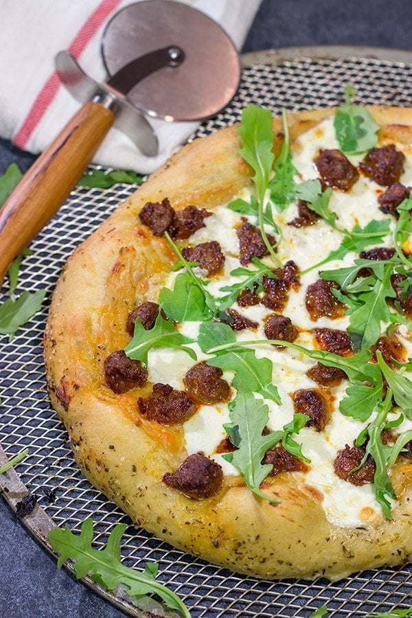 Mix up pizza night!  This Italian Sausage and Alfredo Pizza features a delicious alfredo sauce base topped with juicy Italian sausage and fresh arugula!