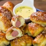Take the classic pigs in a blanket to a new level...by adding cheese and then wrapping them in pretzel dough!  Serve these Pretzel Pigs in a Blanket with a quick and easy honey mustard dipping sauce for extra flavor!