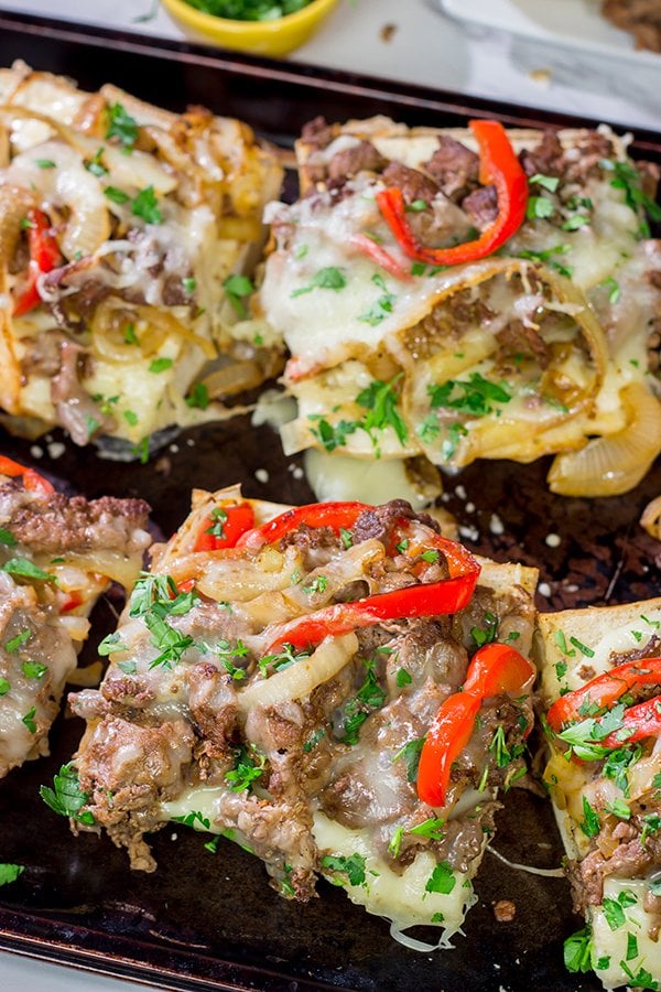 Combine two favorites into one with this Philly Cheesesteak Garlic Bread - shaved steak, peppers + onions, melted cheese...all on top of buttery, garlicky bread!