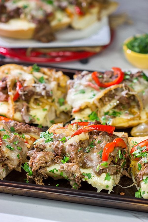 Combine two favorites into one with this Philly Cheesesteak Garlic Bread - shaved steak, peppers + onions, melted cheese...all on top of buttery, garlicky bread!