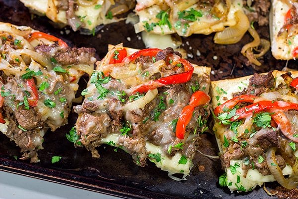 Combine two favorites into one with this Philly Cheesesteak Garlic Bread - shaved steak, peppers + onions, melted cheese...all on top of buttery, garlicky bread!