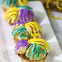 Celebrate Mardi Gras with a batch of these Muffin Tin King Cakes!  Filled with cinnamon + brown sugar flavor, these king cakes make for a festive treat!
