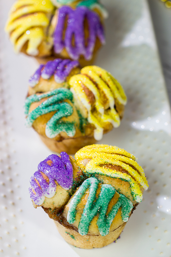 Celebrate Mardi Gras with a batch of these Muffin Tin King Cakes!  Filled with cinnamon + brown sugar flavor, these king cakes make for a festive treat!