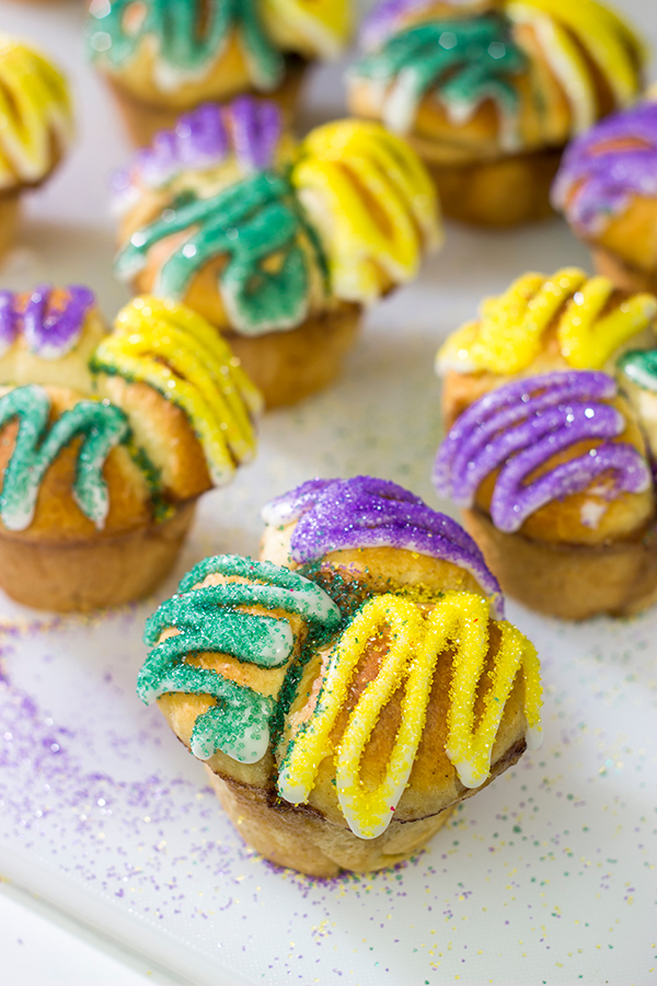 Celebrate Mardi Gras with a batch of these Muffin Tin King Cakes!  Filled with cinnamon + brown sugar flavor, these king cakes make for a festive treat!