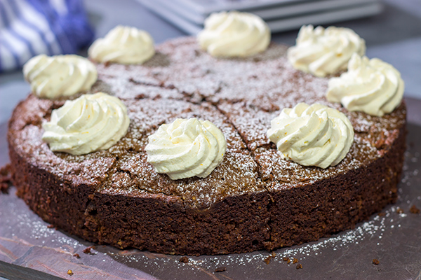 Packed with chocolate and chopped almonds, this Torta Caprese makes for a delicious treat...especially when topped with a dollop of orange-ginger whipped cream!