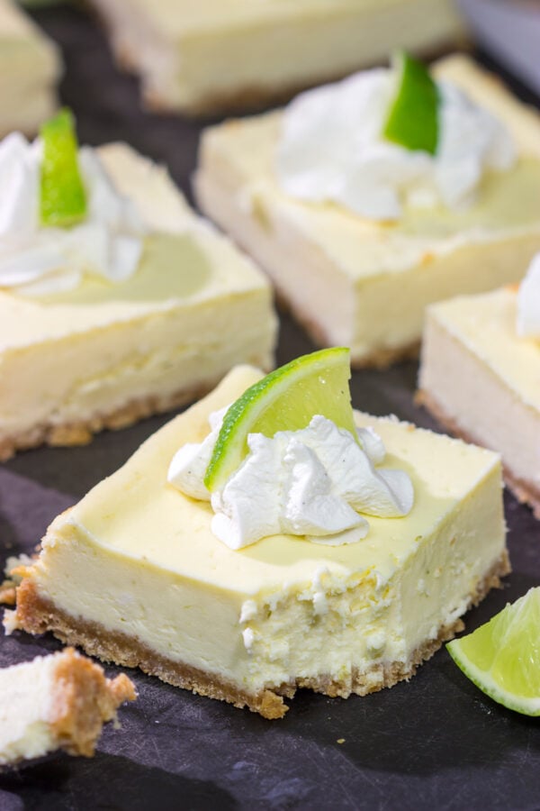 Featuring a hint of tequila + lime flavor in a creamy cheesecake filling, these Margarita Cheesecake Bars are a fun and tasty summer dessert recipe!