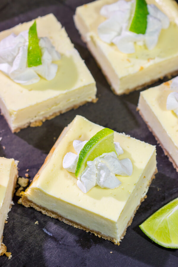 Featuring a hint of tequila + lime flavor in a creamy cheesecake filling, these Margarita Cheesecake Bars are a fun and tasty summer dessert recipe!