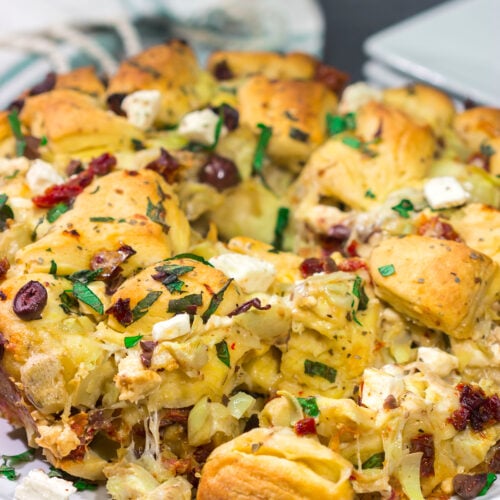 Put a fun spin on monkey bread with this Mediterranean Pull Apart Bread! Think melty cheese, bread, olives, artichokes and sun-dried tomatoes - yum!