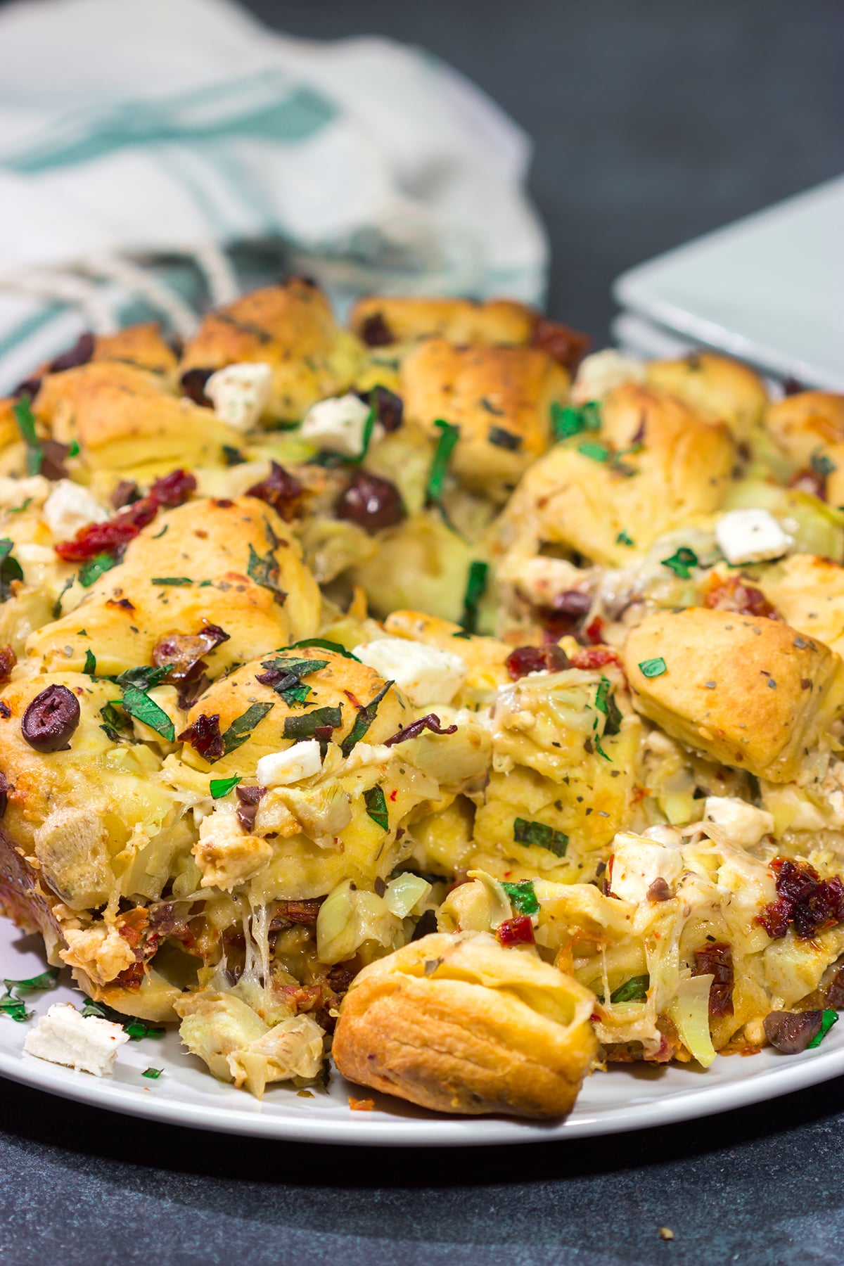 Put a fun spin on monkey bread with this Mediterranean Pull Apart Bread! Think melty cheese, bread, olives, artichokes and sun-dried tomatoes - yum!