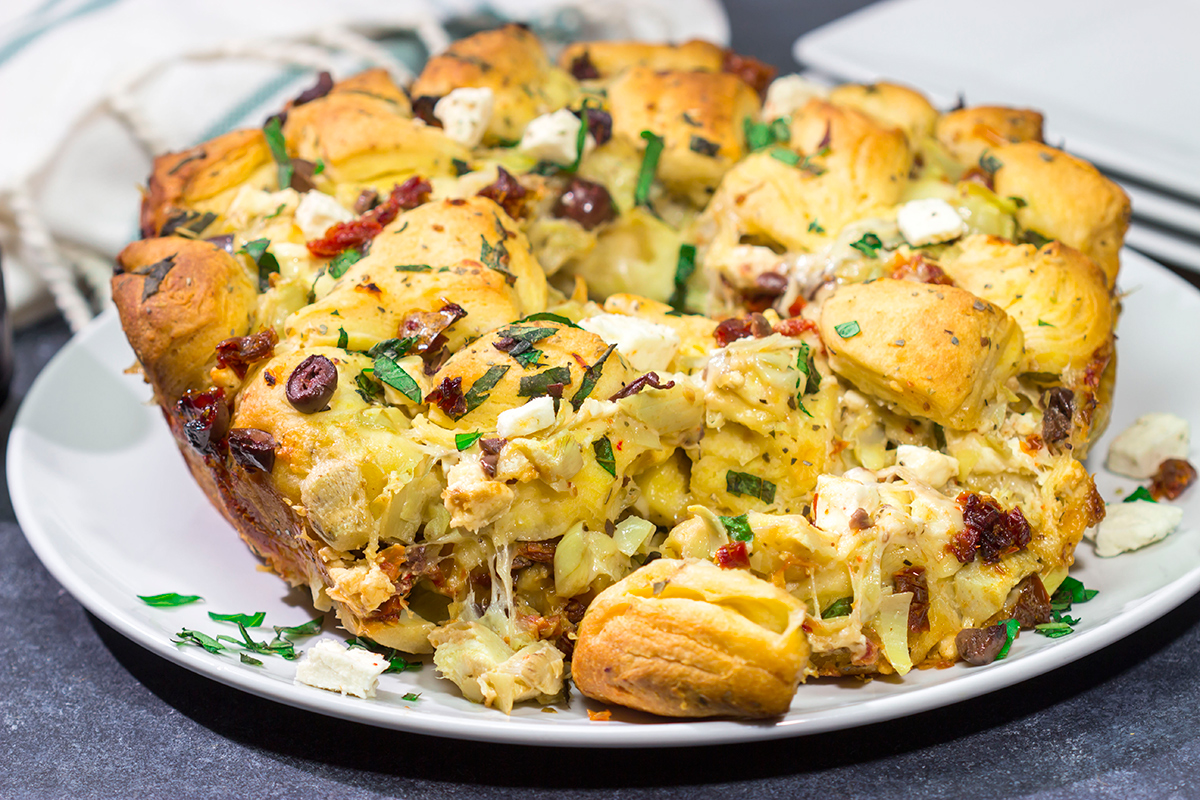 Put a fun spin on monkey bread with this Mediterranean Pull Apart Bread! Think melty cheese, bread, olives, artichokes and sun-dried tomatoes - yum!