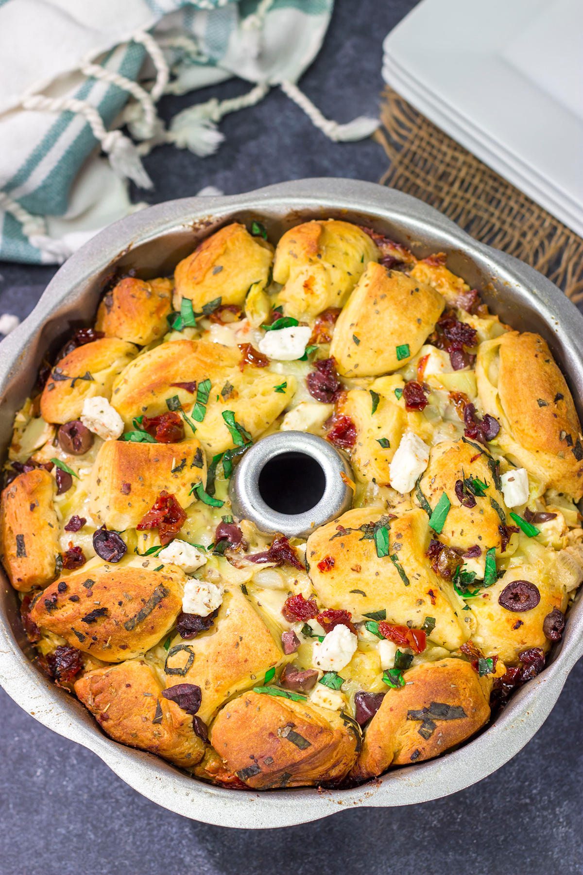 Put a fun spin on monkey bread with this Mediterranean Pull Apart Bread! Think melty cheese, bread, olives, artichokes and sun-dried tomatoes - yum!