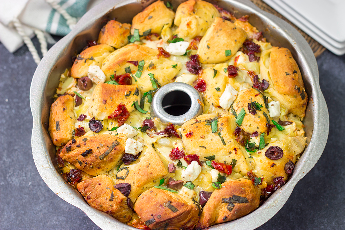 Put a fun spin on monkey bread with this Mediterranean Pull Apart Bread! Think melty cheese, bread, olives, artichokes and sun-dried tomatoes - yum!