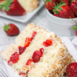 This Coconut Strawberry Cake features 3 layers of soft white cake topped with cream cheese frosting and toasted coconut. It's perfect for summer!