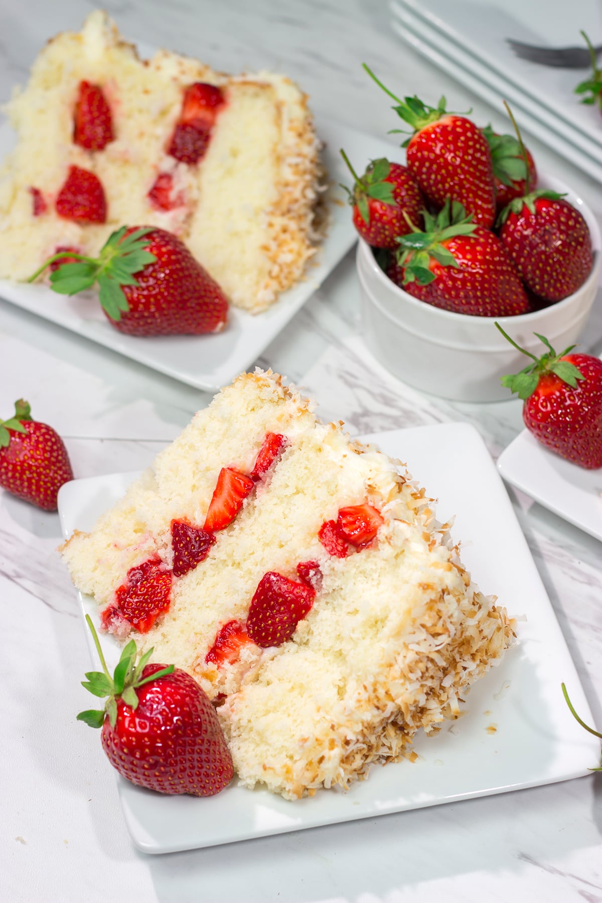 This Coconut Strawberry Cake features 3 layers of soft white cake topped with cream cheese frosting and toasted coconut. It's perfect for summer!