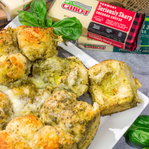 This Cheesy Pesto Pull Apart Bread features freshly baked bread layered with two types of cheese and basil pesto. It's perfect for tailgating or game nights with friends!