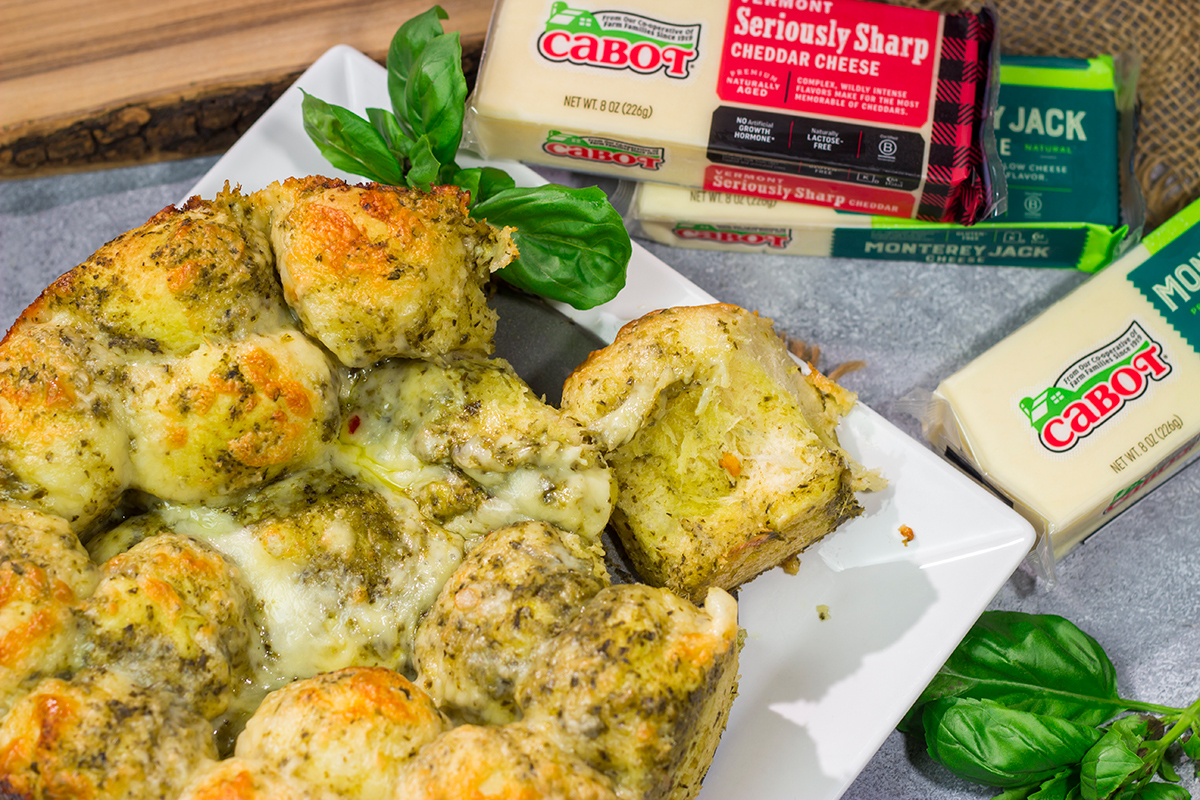 This Cheesy Pesto Pull Apart Bread features freshly baked bread layered with two types of cheese and basil pesto. It's perfect for tailgating or game nights with friends!