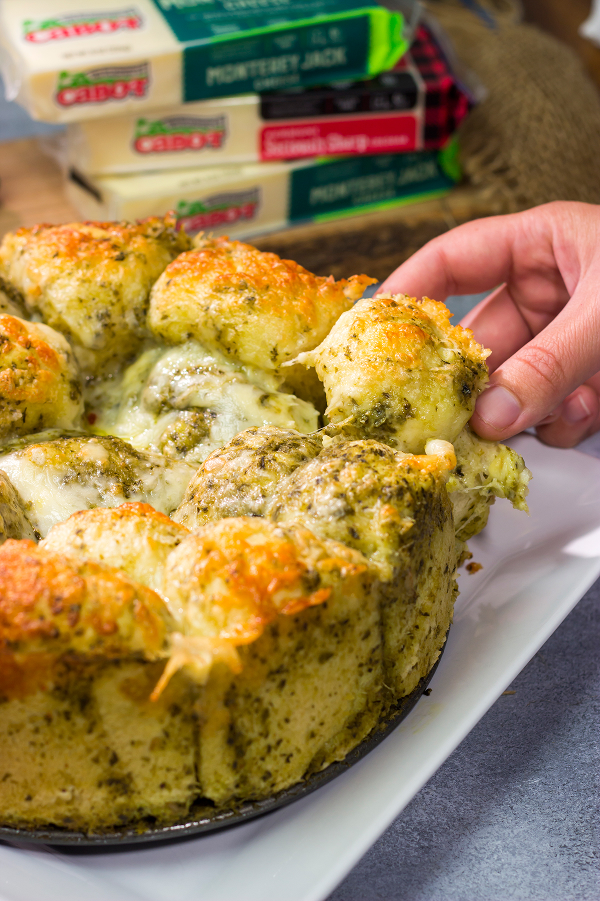 This Cheesy Pesto Pull Apart Bread features freshly baked bread layered with two types of cheese and basil pesto. It's perfect for tailgating or game nights with friends!