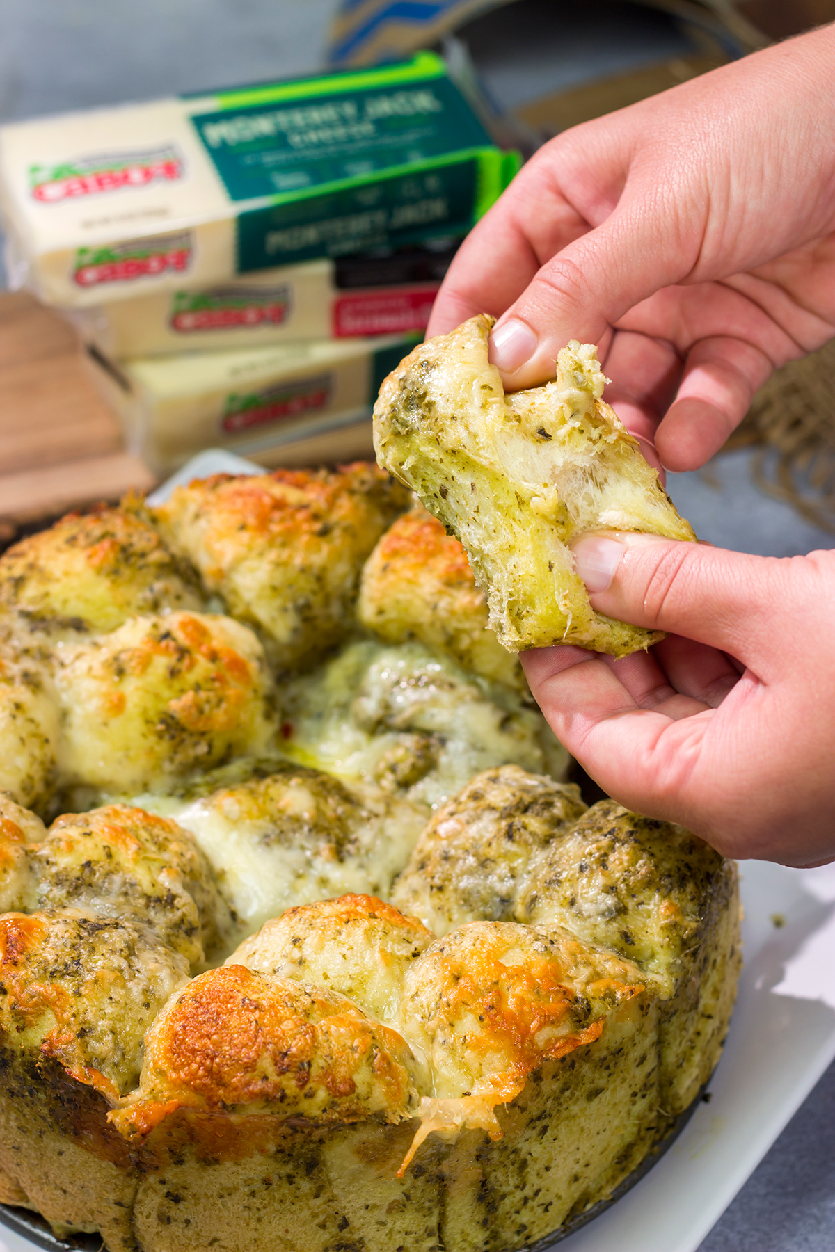 This Cheesy Pesto Pull Apart Bread features freshly baked bread layered with two types of cheese and basil pesto. It's perfect for tailgating or game nights with friends!