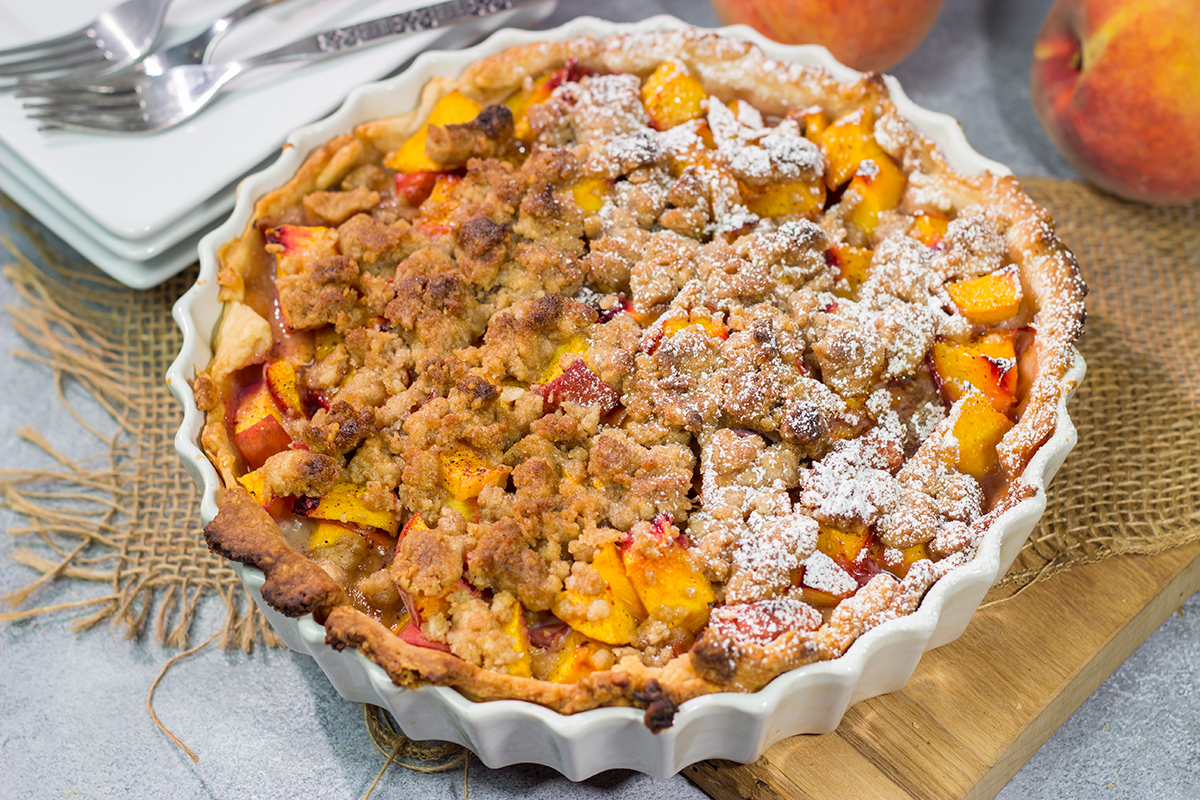 This Peach Crumble Pie features ripe peaches combined with brown sugar and nutmeg. The filling goes on top of a flaky, buttery crust and then a cinnamon sugar crumble gets sprinkled on top. Add a scoop of vanilla ice cream for the perfect summer dessert!