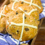Combine two favorite Easter recipes into one with these Carrot Cake Hot Cross Buns! These spiced buns includes carrots, raisins and chopped walnuts.