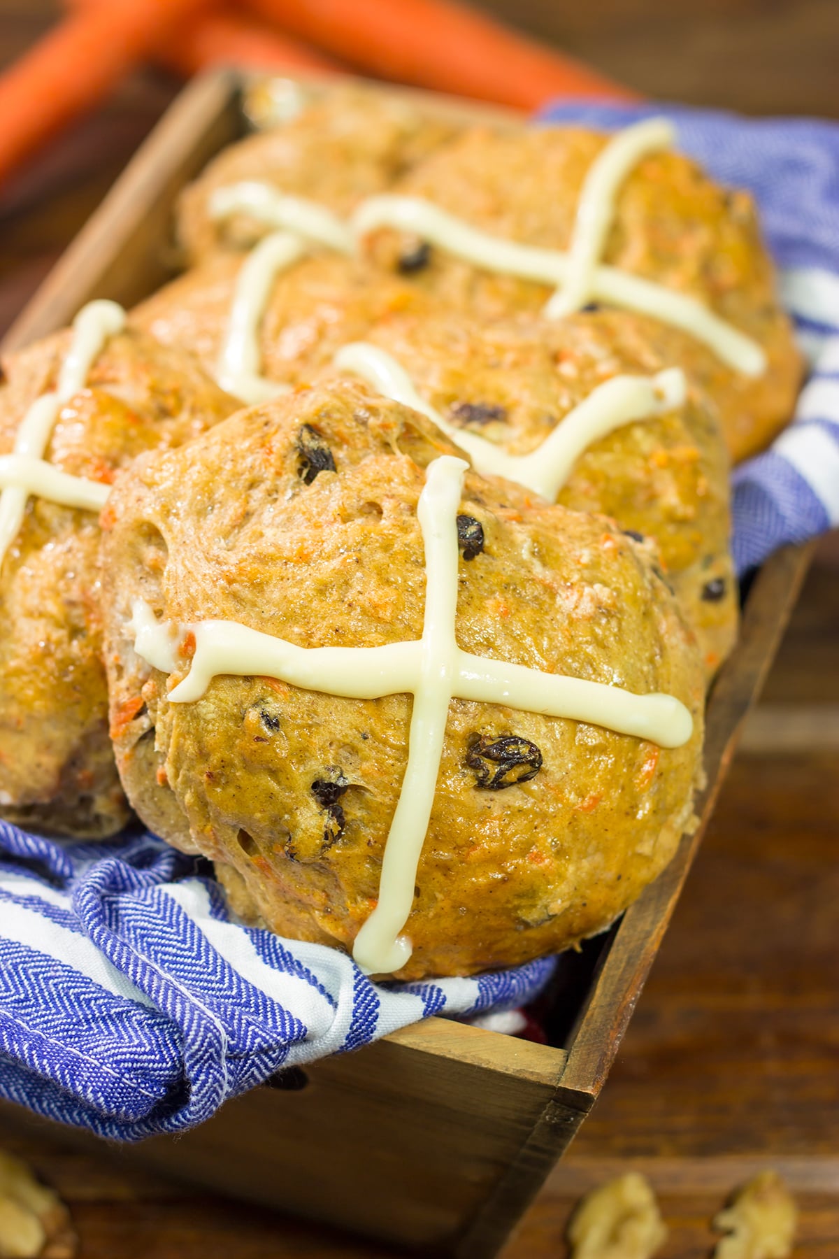Combine two favorite Easter recipes into one with these Carrot Cake Hot Cross Buns! These spiced buns includes carrots, raisins and chopped walnuts.
