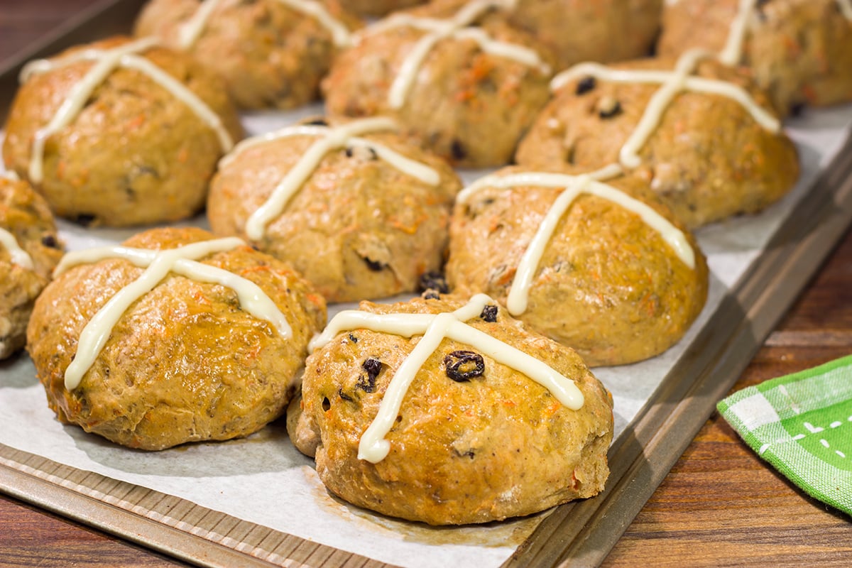 Combine two favorite Easter recipes into one with these Carrot Cake Hot Cross Buns! These spiced buns includes carrots, raisins and chopped walnuts.